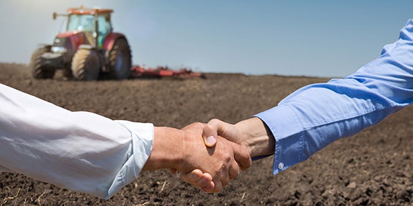 business partners shaking hands on a piece of farm land